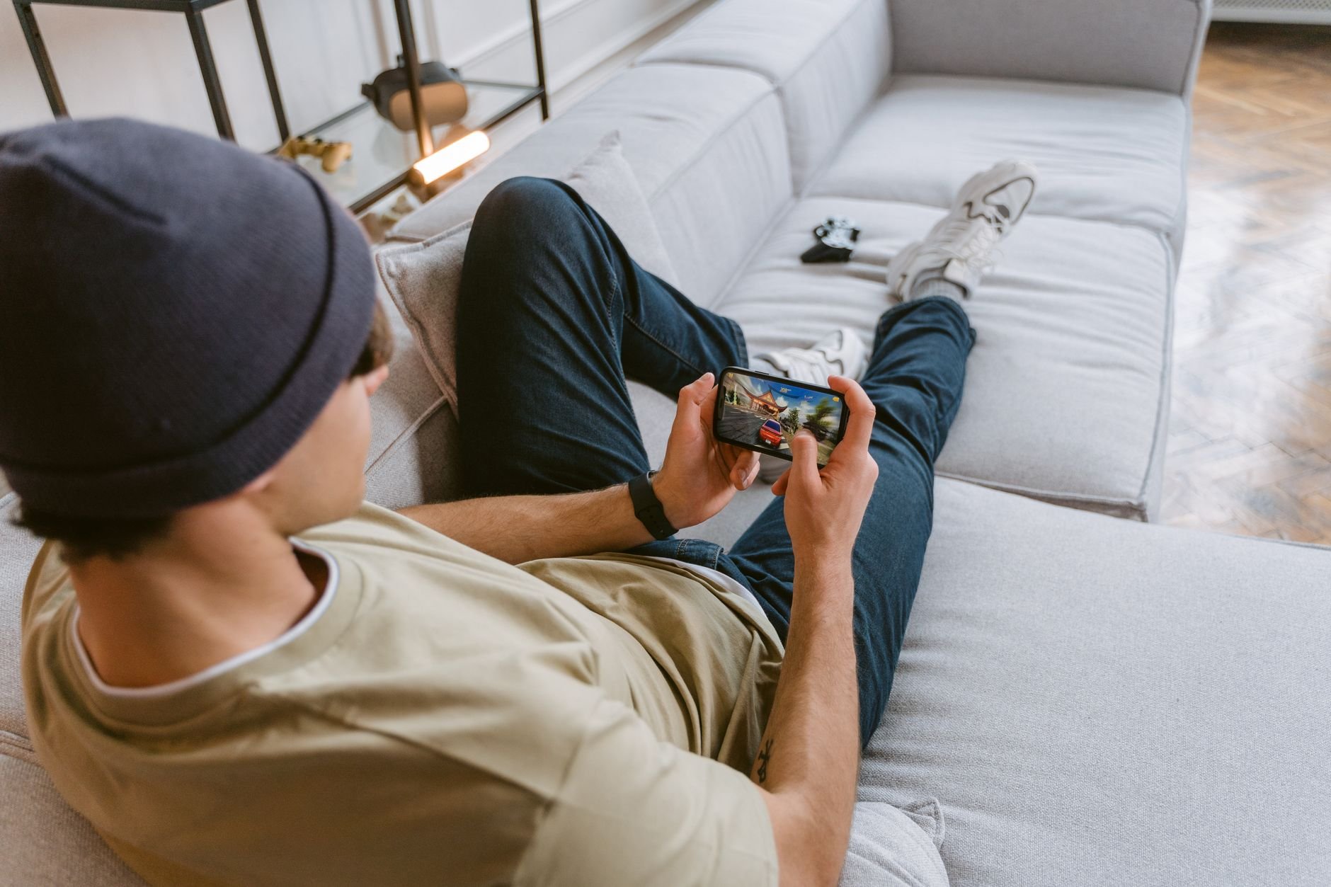 A man relaxing on a sofa, playing a mobile game